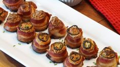 bacon wrapped in cheese on a white plate next to a red napkin and cupcakes