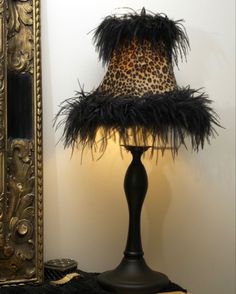 a lamp that is sitting on a table next to a mirror and a leopard print lampshade