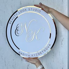 a person holding up a white and gold plate with the words beauty look studio on it