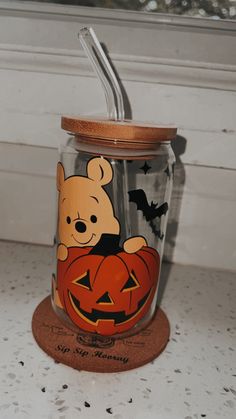 a winnie the pooh pumpkin jar with a straw in it sitting on a counter