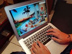 a person is using a laptop computer on the floor with palm trees in the background