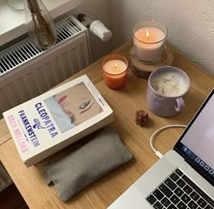 an open laptop computer sitting on top of a wooden desk next to a cup of coffee