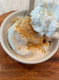 a bowl filled with whipped cream on top of a wooden table