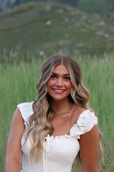 a beautiful young woman in a white dress posing for the camera with her hands on her hips