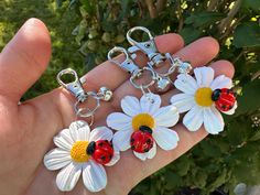 ladybug keychains with daisies on them are being held by someone's hand