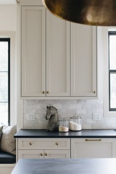 a kitchen with white cabinets, black counter tops and a horse head on the island