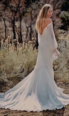 a woman in a white dress is walking through the desert with her back to the camera