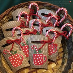 some candy canes are sitting in a basket with tags on the handles and bows around them