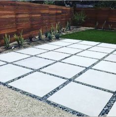 a concrete patio with grass and wooden fence in the background