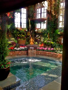 an indoor swimming pool surrounded by flowers and greenery in the middle of a courtyard