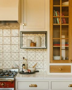 a stove top oven sitting inside of a kitchen next to a wooden cabinet filled with books