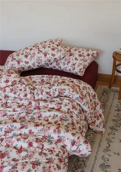 an unmade bed with floral sheets and pillows