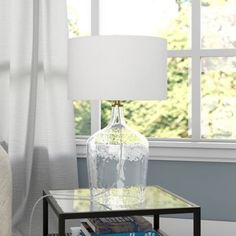 a glass table with a book and lamp on it