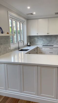 an empty kitchen with white cabinets and wood floors