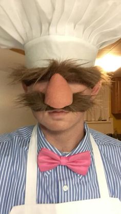 a man wearing a chef hat and bow tie with fake moustache on his face