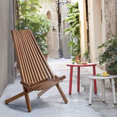 a wooden chair sitting on top of a cement floor next to a table and chairs