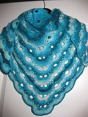 a blue crocheted shawl hanging from a hook on a door way with holes in it