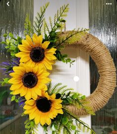 a wreath with three sunflowers hanging from it's side on a door