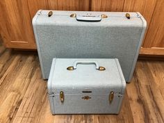 two suitcases sitting next to each other on the floor in front of wooden cabinets