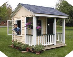 a small white shed with flowers in the window and on the front porch next to it