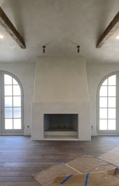 an empty room with two windows and a fireplace