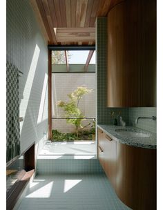 a bathroom with tiled walls and flooring next to a window that looks out onto a garden