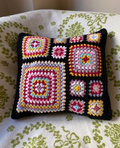 a crocheted pillow is sitting on a chair