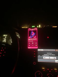 a cell phone sitting on the dashboard of a car in the dark at night time