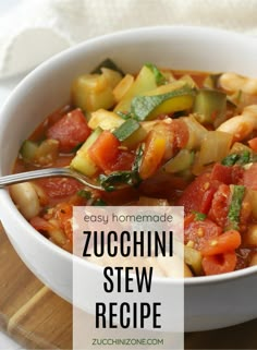 a white bowl filled with zucchini stew on top of a wooden cutting board