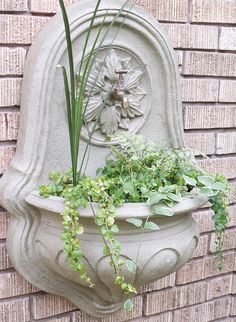 a planter with plants growing in it on the side of a brick wall next to a building