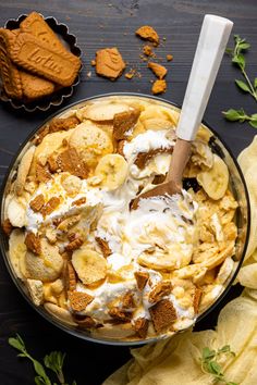 a bowl filled with bananas and whipped cream on top of a table next to cookies