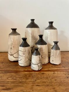 five ceramic vases sitting on top of a wooden table