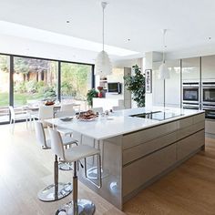 a modern kitchen with stainless steel appliances and white counter tops, along with an island