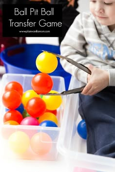 a young boy is playing with balls in a plastic container and using scissors to cut them