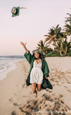 a woman in white dress and green jacket flying a kite on the beach with palm trees