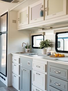 a kitchen with white cabinets and gray counter tops next to an open refrigerator freezer