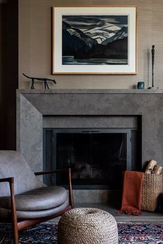 a living room with a fire place, chair and painting on the fireplace mantel