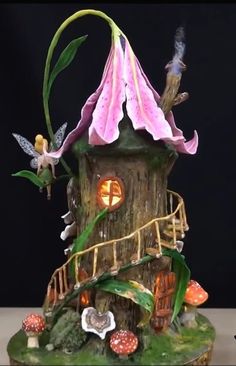 a small tree house with flowers and fairy figurines