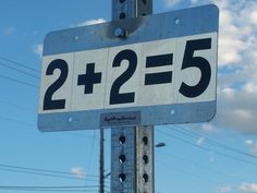 a close up of a street sign with power lines in the background and clouds in the sky