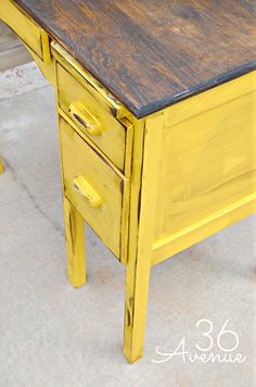 an old yellow desk with two drawers is painted bright yellow and has been turned into a side table