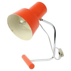 an orange and white desk lamp on a metal stand with a light bulb attached to it