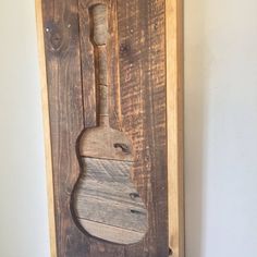 a wooden wall hanging with a guitar on it's side and a bottle opener in the middle