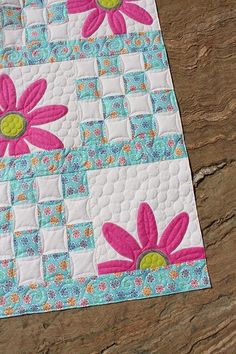 a quilted table runner with pink flowers on it