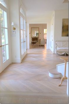 an empty hallway with white furniture and large windows on both sides, leading to the dining room