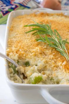 a casserole dish with cheese and vegetables in it on a white plate next to a spoon