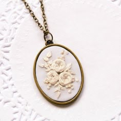 a necklace with flowers on it sitting on top of a white tablecloth covered surface