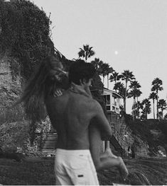 black and white photograph of two people on the beach with palm trees in the background