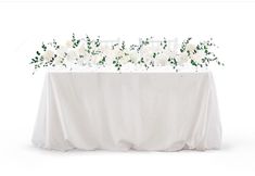 the table is covered with white flowers and greenery for an elegant touch to the wedding reception