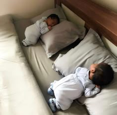 two small children sleeping on pillows in a bed with white sheets and pillowcases