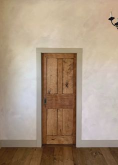 an empty room with a wooden door and chandelier